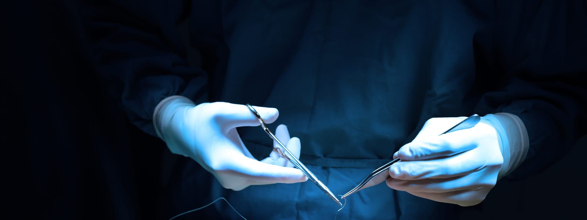 Gloved hands with fine surgical instruments